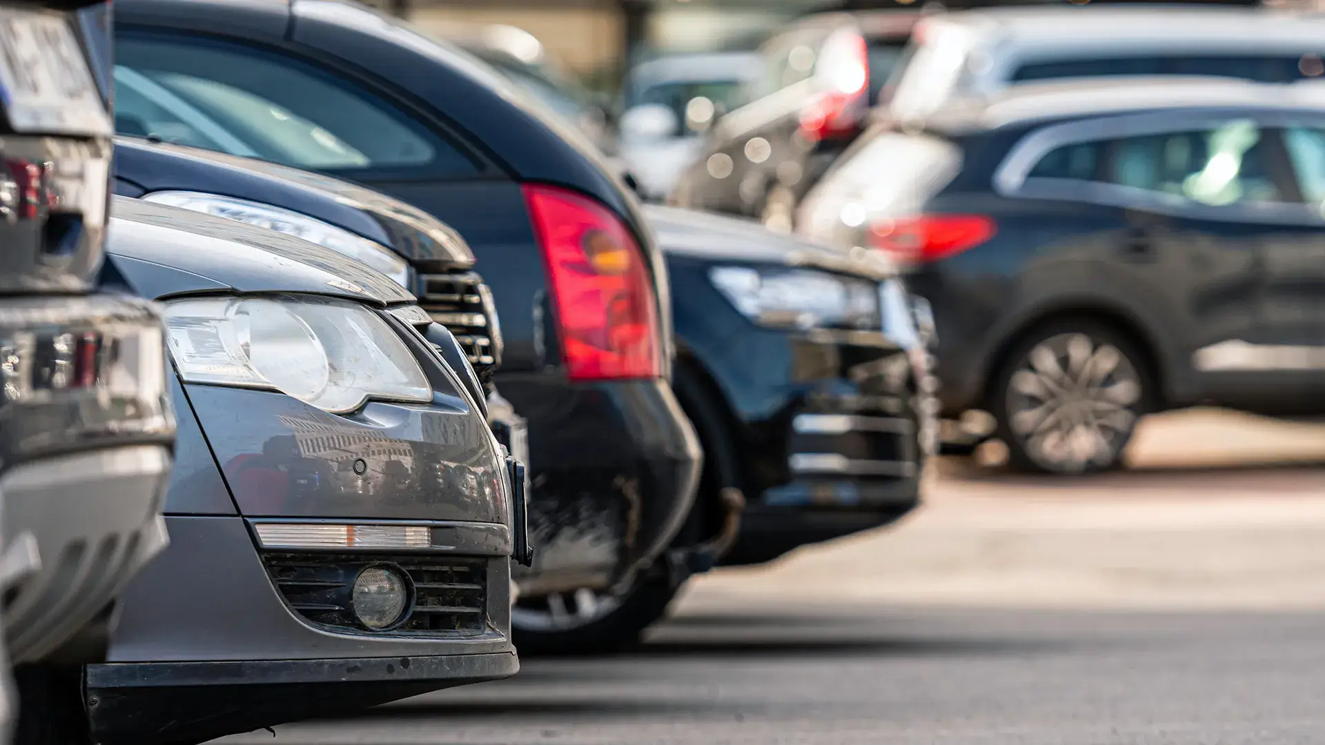 Coches estacionados en fila en un aparcamiento al aire libre.