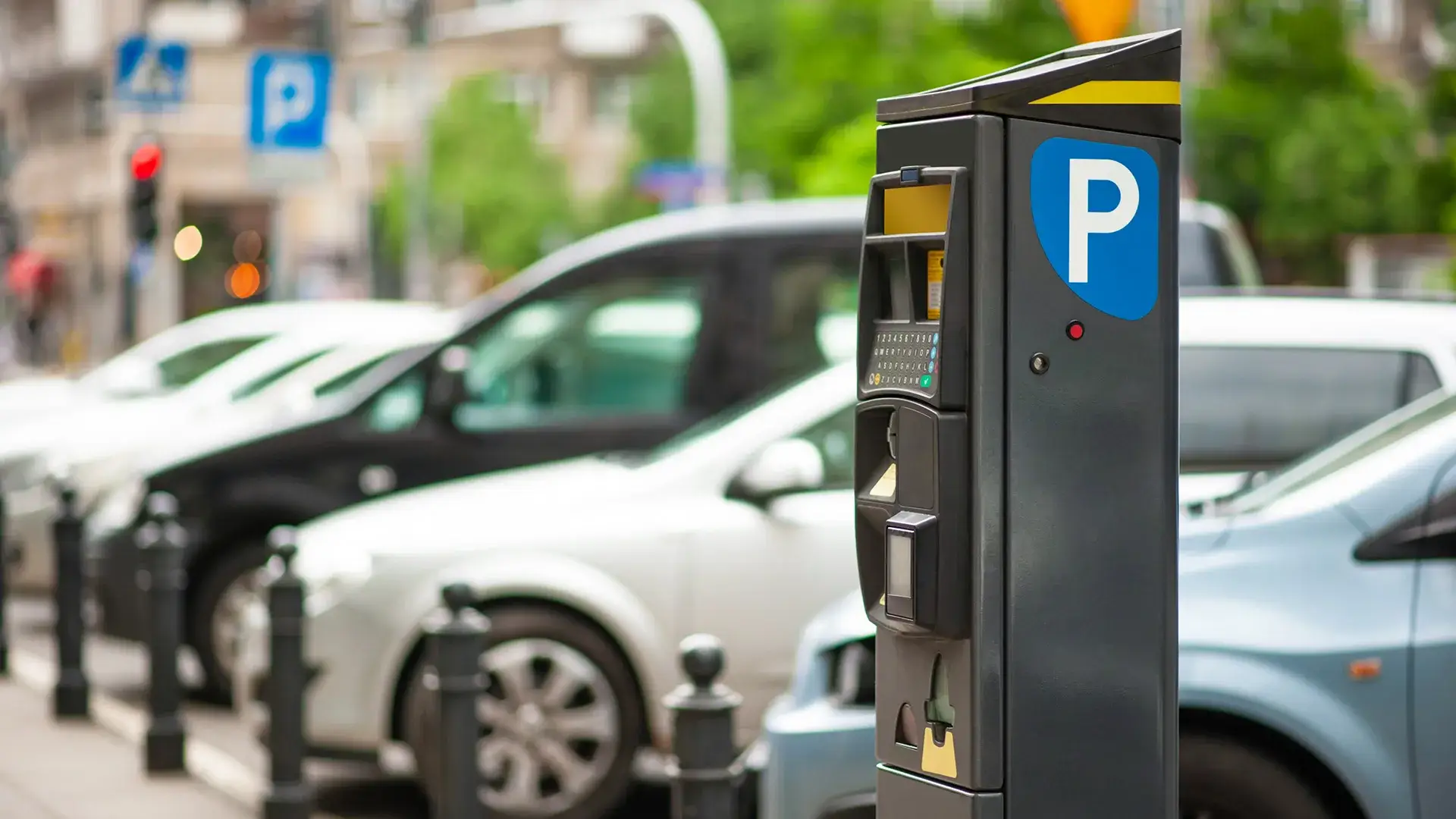 Parqu&iacute;metro en una calle con autos estacionados al fondo.