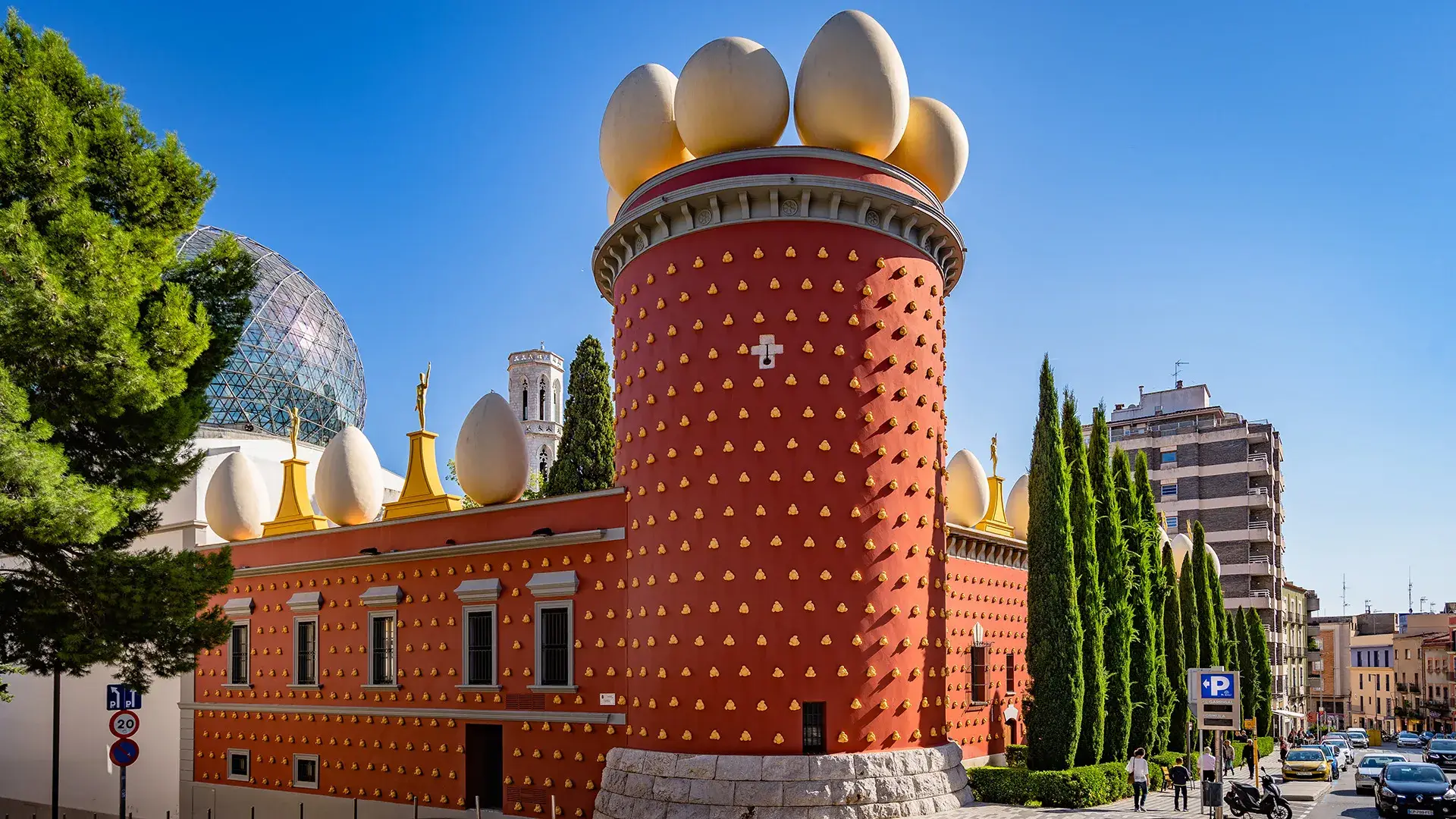 Edificio surrealista con fachada roja y adornos de huevos gigantes arriba.