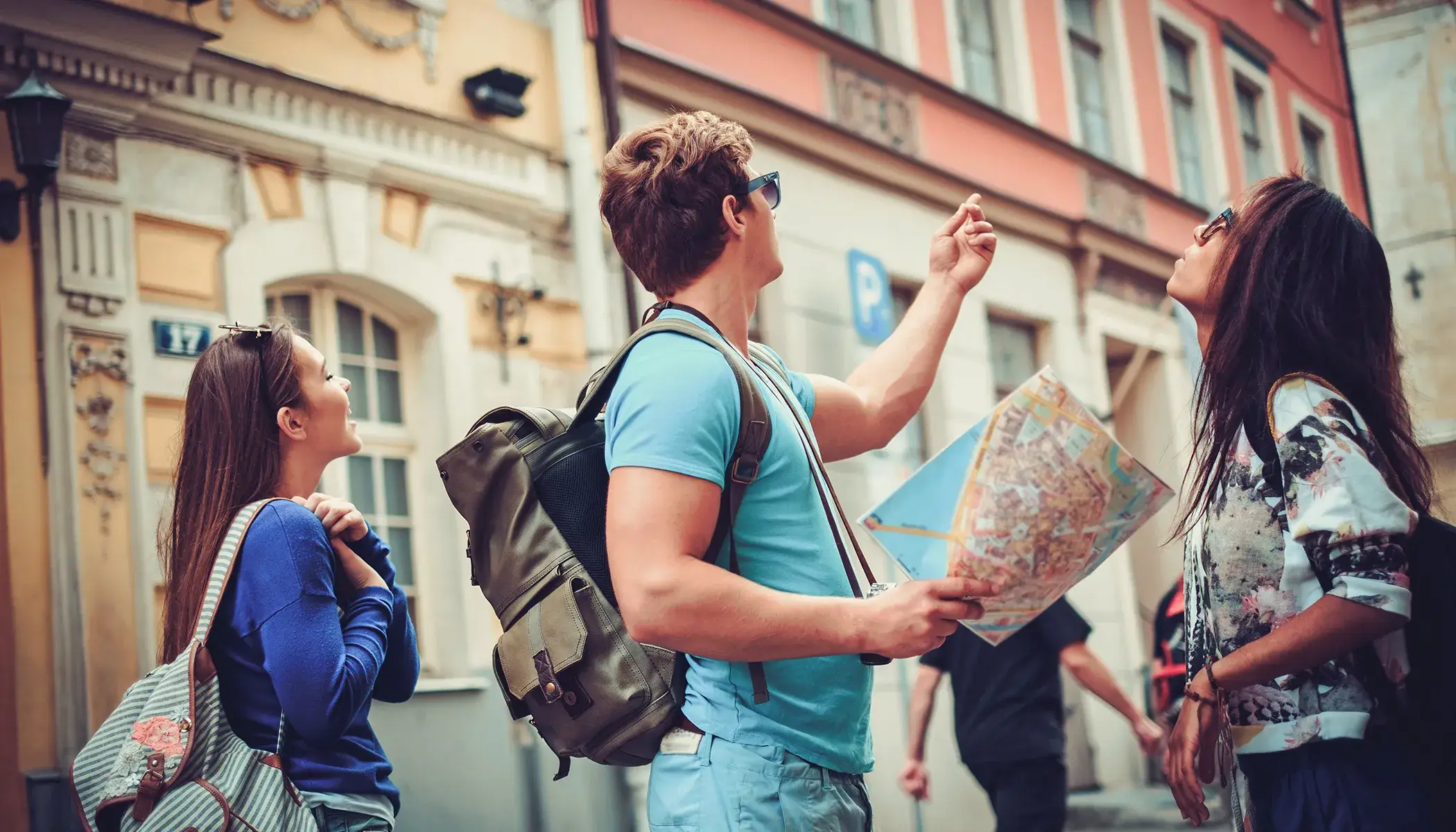 Tres personas con un mapa exploran una calle con edificios antiguos.