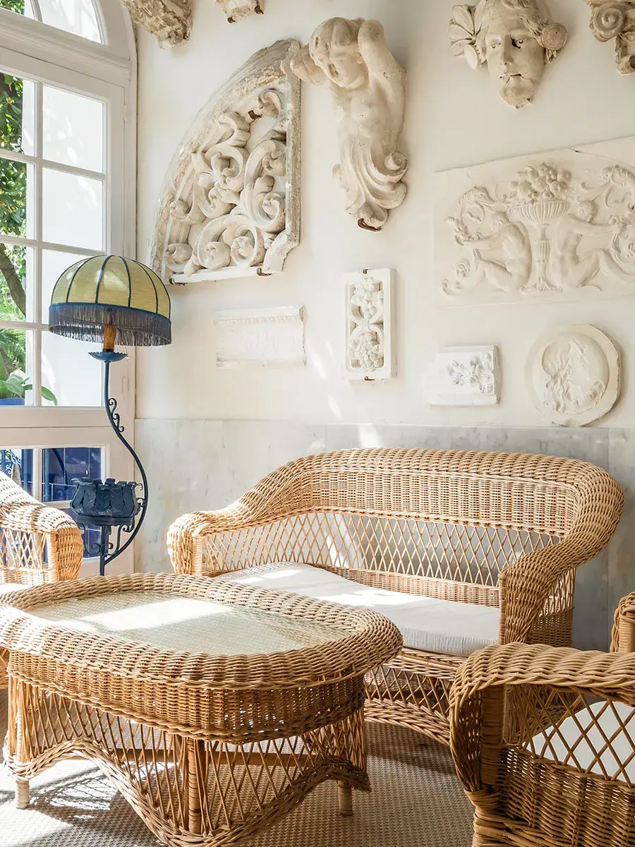Sala con mimbre, l&aacute;mpara vintage y relieves decorativos en la pared.
