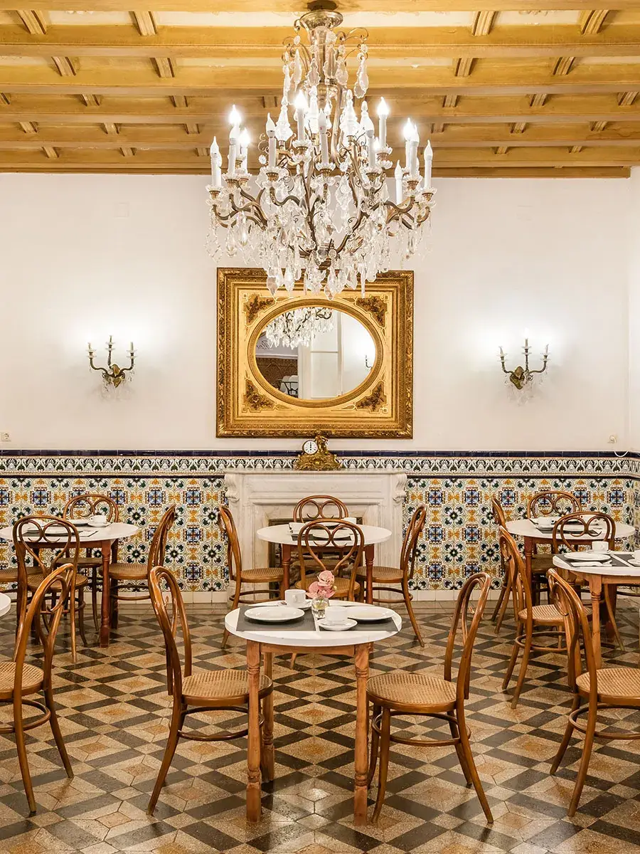 Cafeter&iacute;a con mesas, sillas y candelabro, decoraci&oacute;n cl&aacute;sica y elegante.