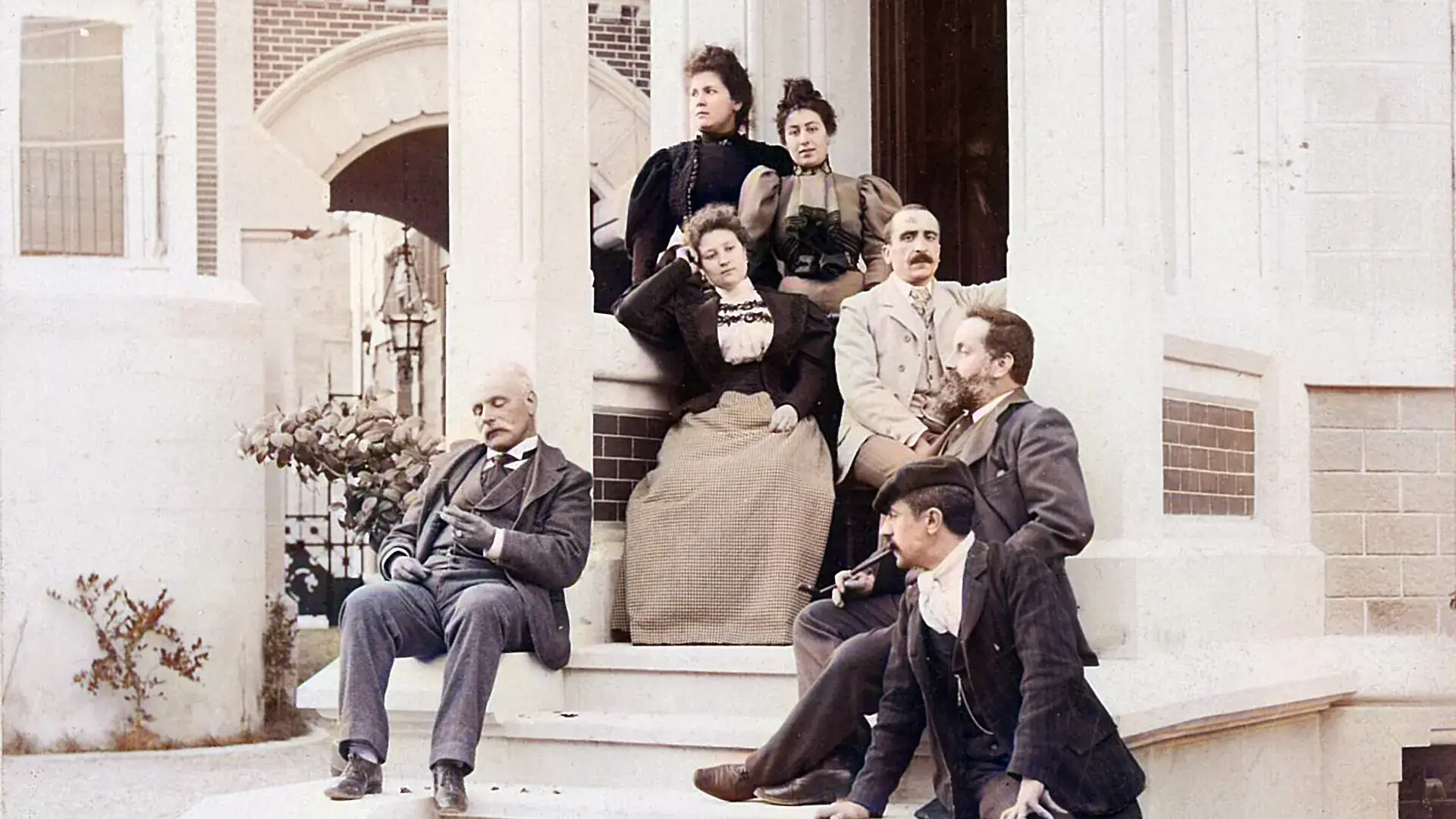Grupo de personas de &eacute;poca sentadas en escaleras de un edificio elegante.