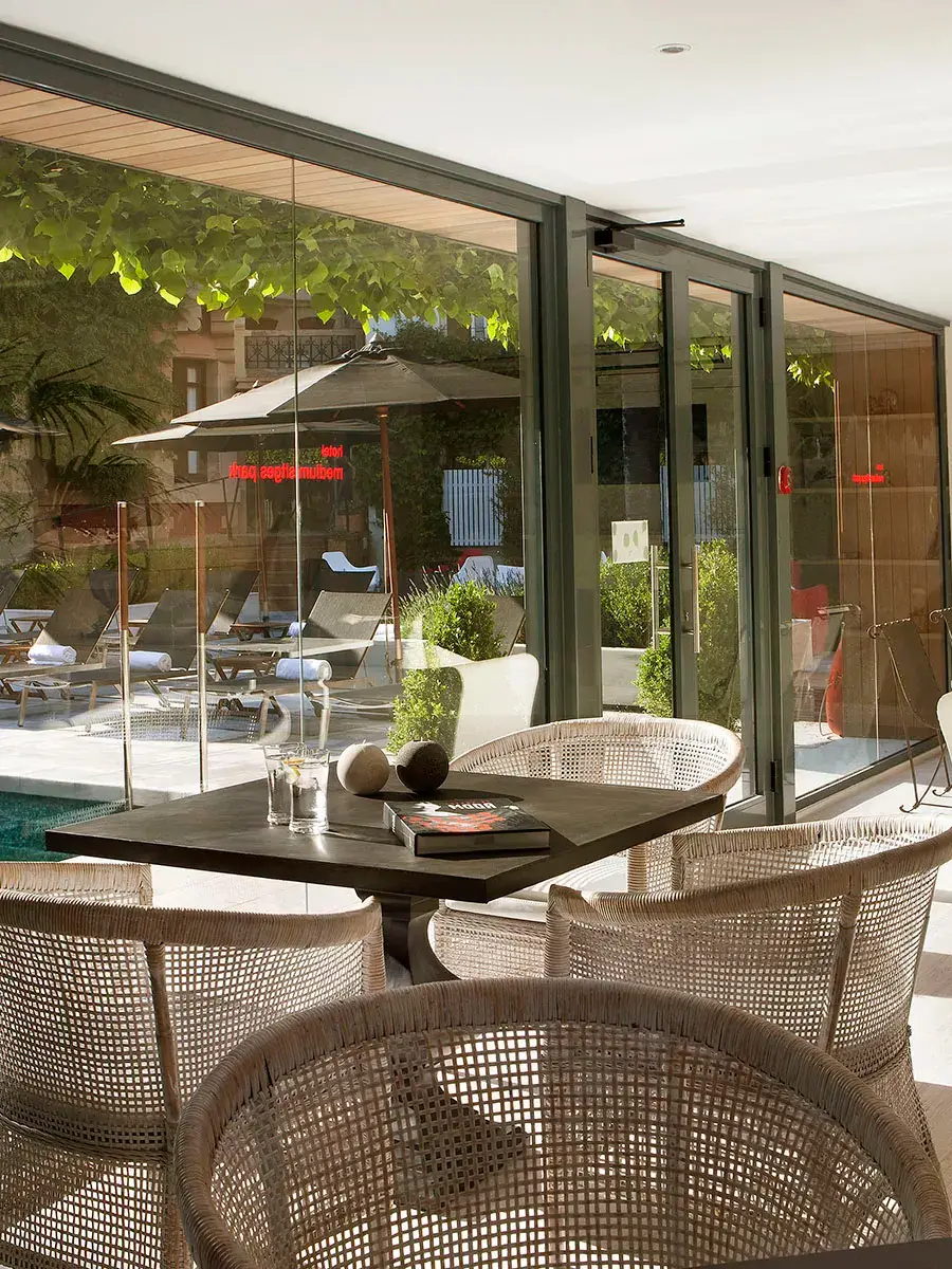 Terraza moderna con sillas de mimbre y mesa cerca de una piscina.