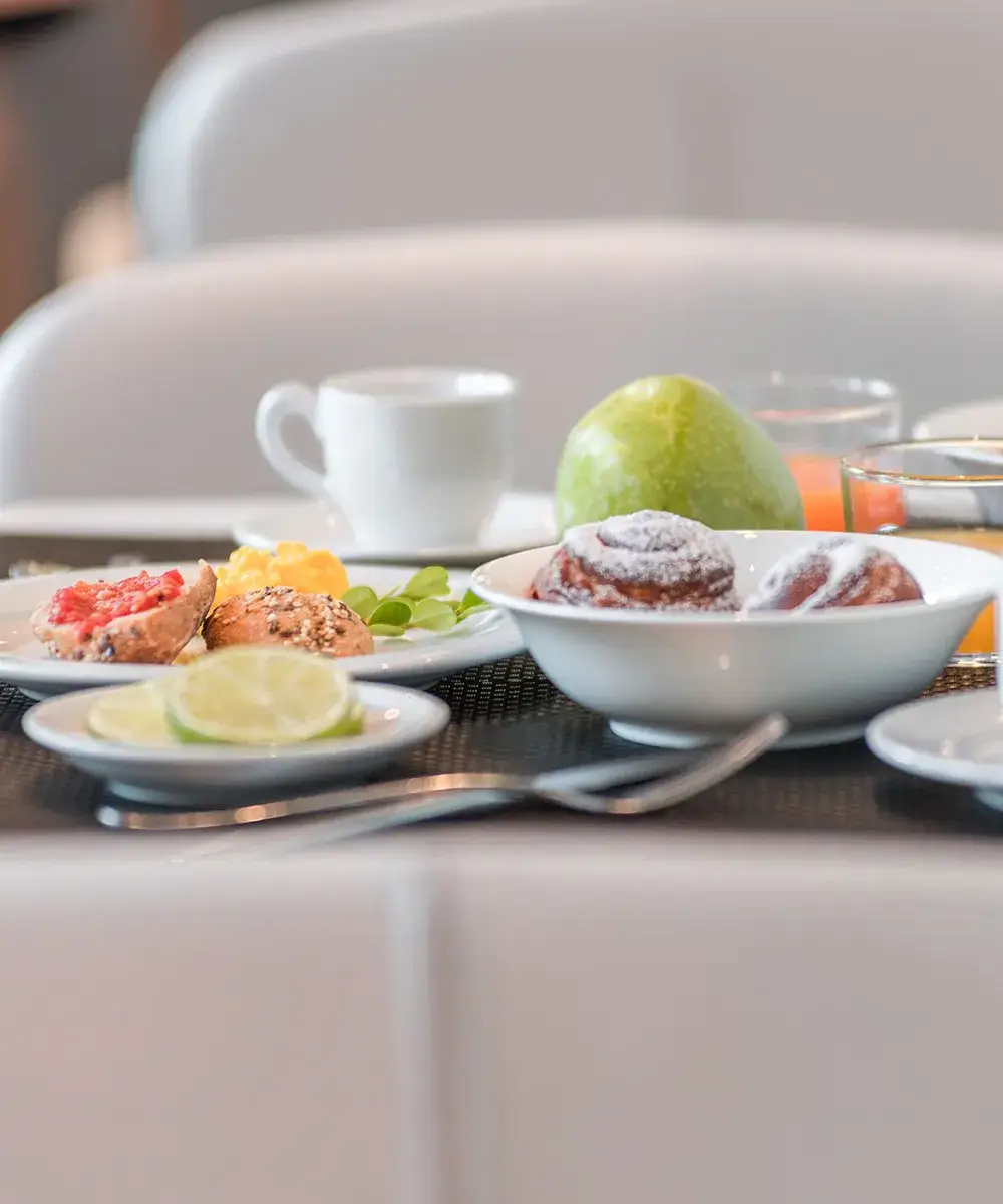 Desayuno con bollos, fruta y caf&eacute; sobre la mesa.