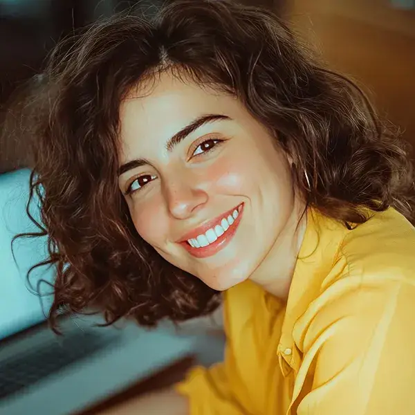 Una persona sonriente con cabello rizado y camisa amarilla.