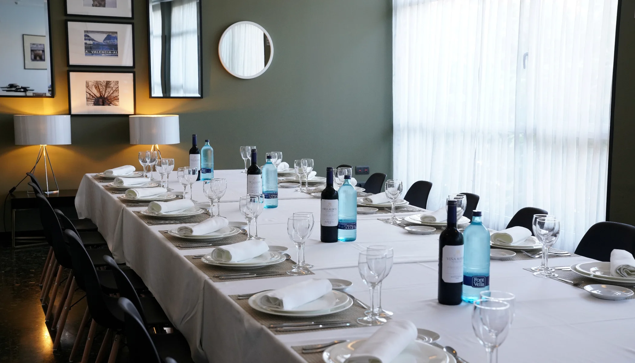 Mesa grande con copas, vajilla y botellas; decoraci&oacute;n elegante y moderna.