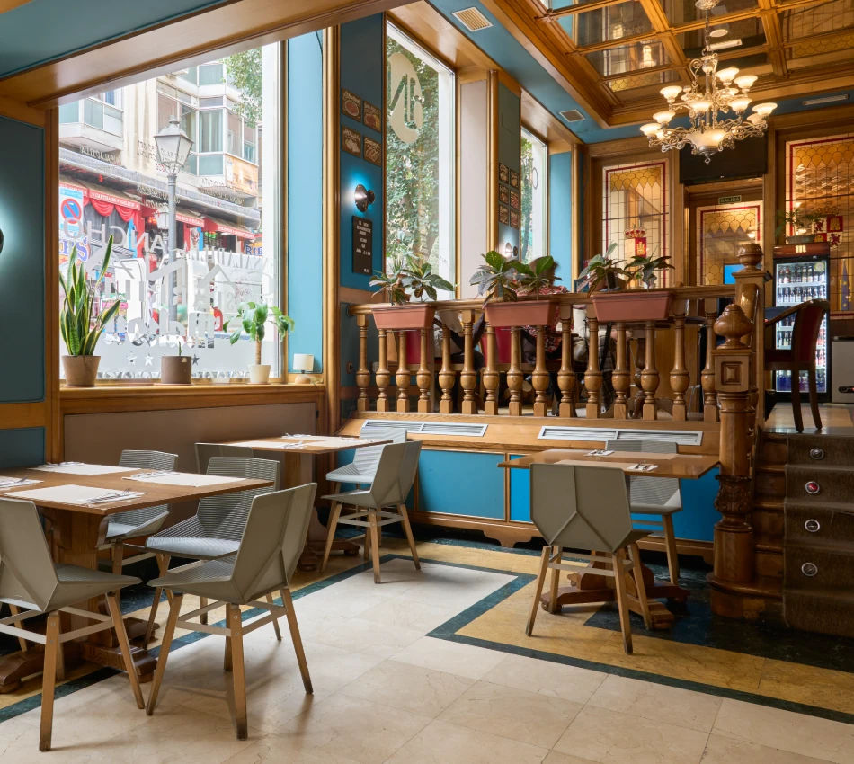 Interior de un restaurante elegante con sillas y mesas de madera y luces c&aacute;lidas.