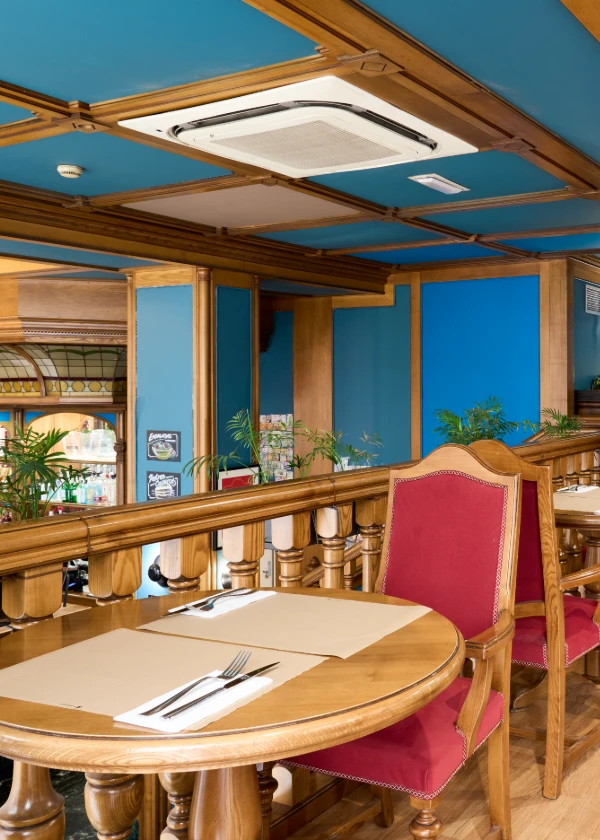 Comedor en un restaurante con sillas rojas y techo azul con aire acondicionado.