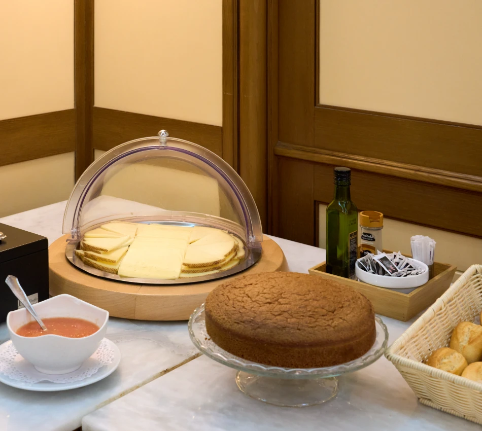 Mesa con pastel, lonchas de queso, pan, aceite y salsa sobre mostrador.