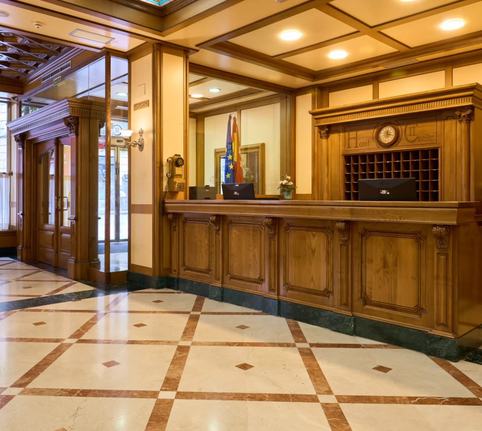 Recepci&oacute;n de hotel cl&aacute;sico, mostrador de madera y banderas decorando.