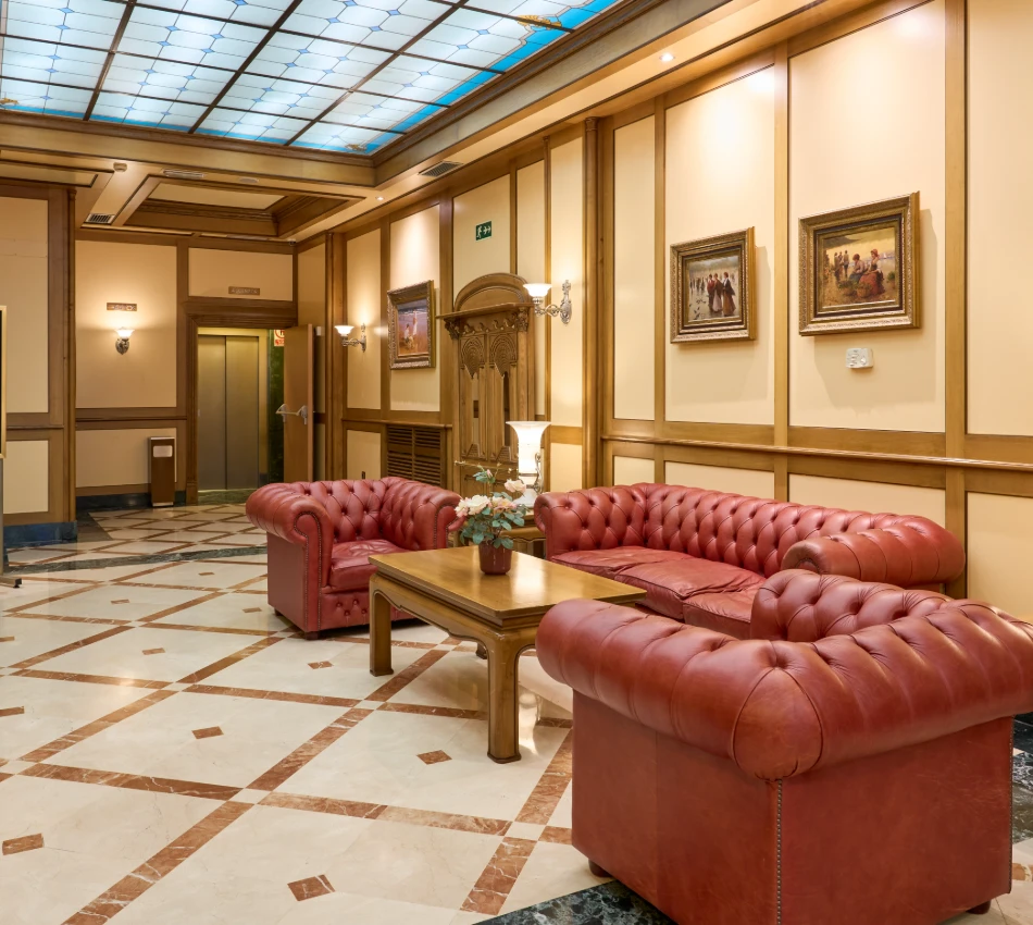 Sala acogedora con sof&aacute;s rojos, mesa de madera y cuadros en la pared.