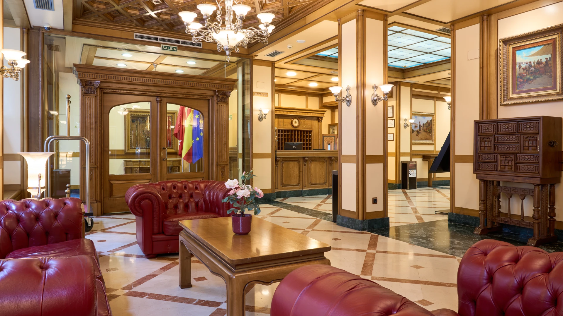 Vest&iacute;bulo elegante con muebles de cuero rojo y l&aacute;mparas cl&aacute;sicas.