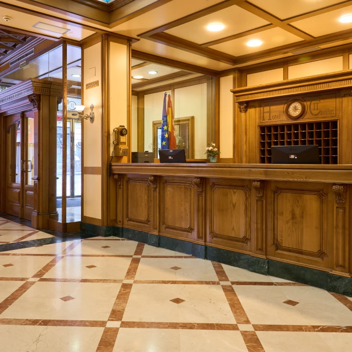 Vest&iacute;bulo de hotel elegante con mostrador de madera y suelos de m&aacute;rmol.