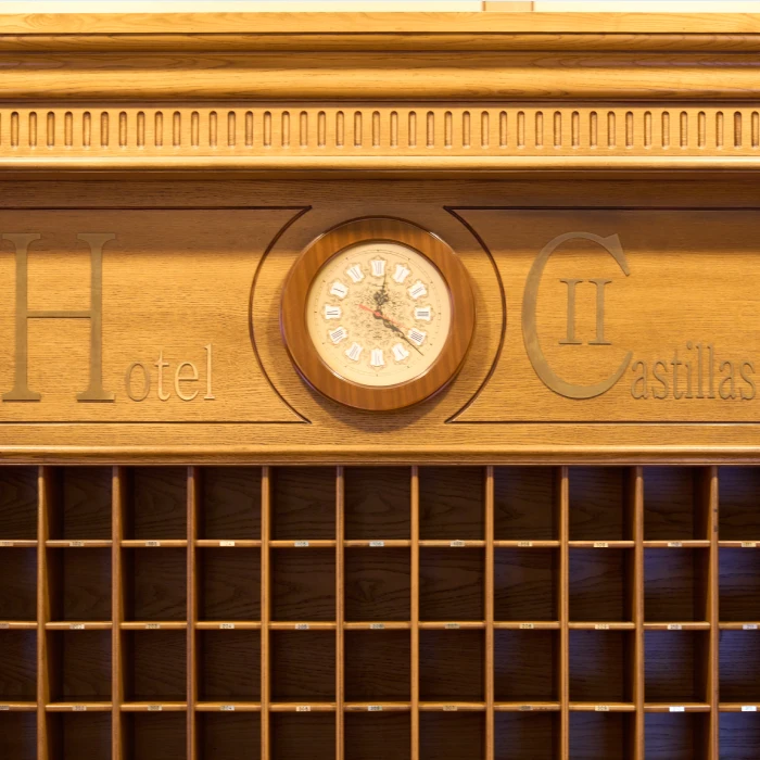 Reloj y casilleros de un hotel de madera con el texto "Hotel II Castillas".