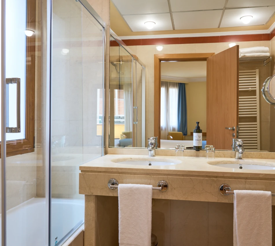 Ba&ntilde;o moderno con lavamanos doble y toallas colgadas.