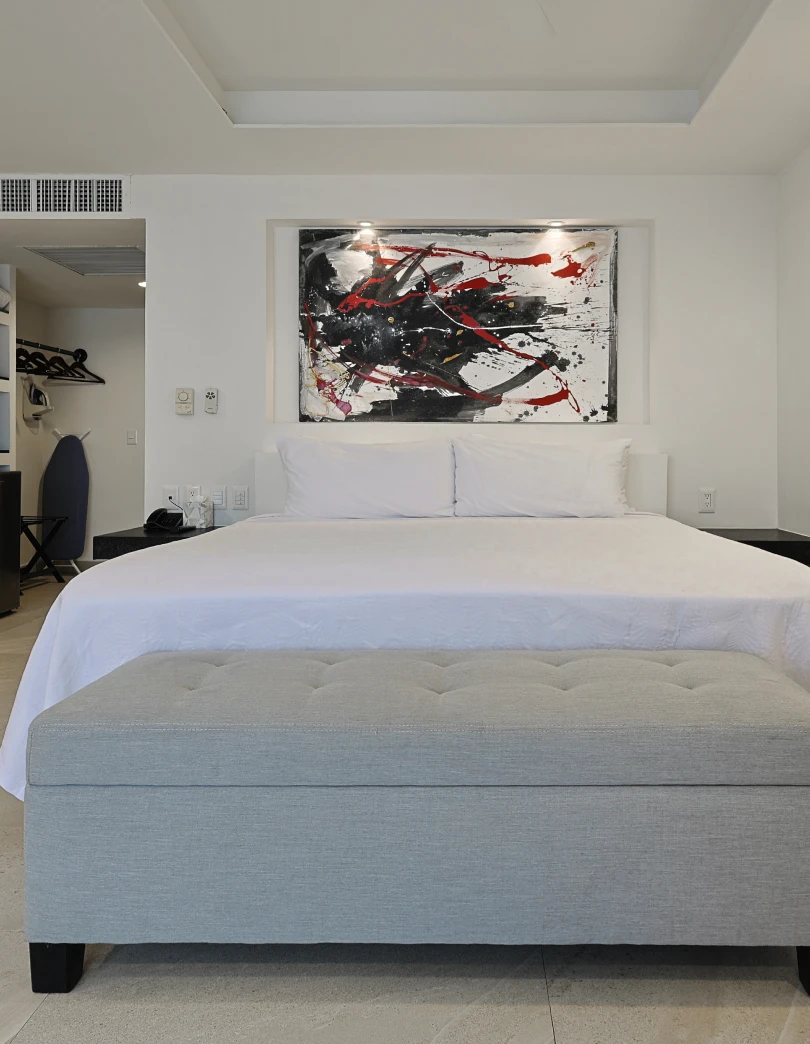 Dormitorio moderno y minimalista con cama doble y cuadro abstracto.