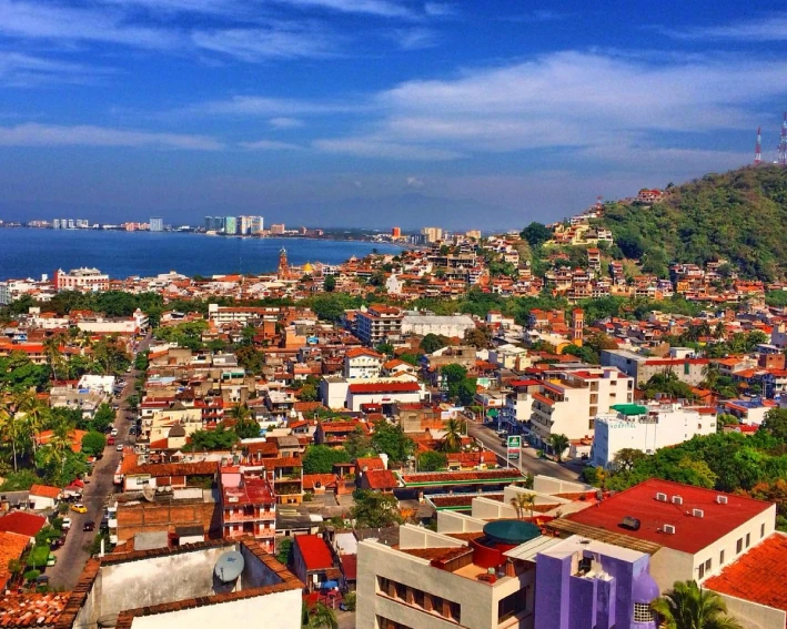 Vista de la ciudad costera, con colinas verdes y el mar de fondo.