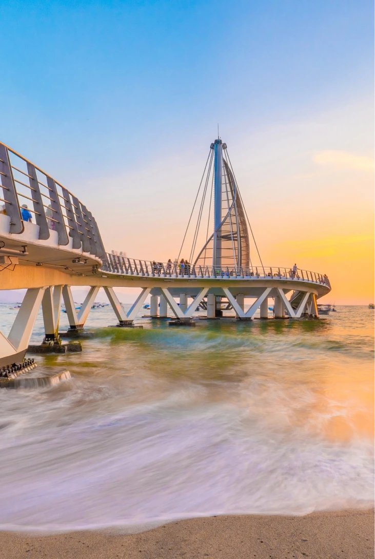 Muelle sobre el mar al atardecer, con personas paseando y cielo despejado.