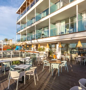 Terraza de un restaurante frente a un edificio moderno y soleado.