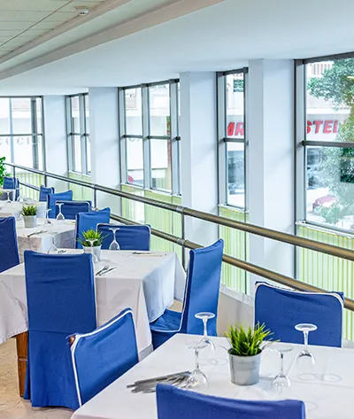 Restaurante moderno con mesas y sillas azules junto a grandes ventanas.