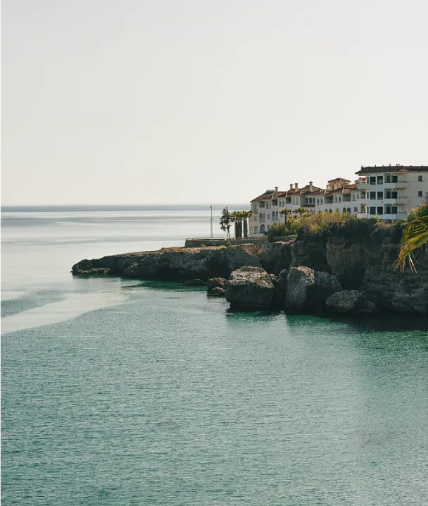 Edificios junto a un acantilado con vistas al mar en un d&iacute;a soleado.
