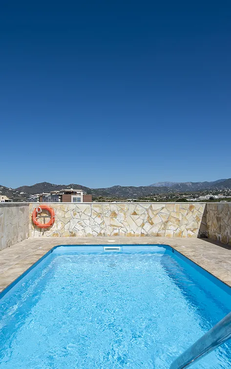 Piscina en terraza con vista a monta&ntilde;as y cielo despejado.