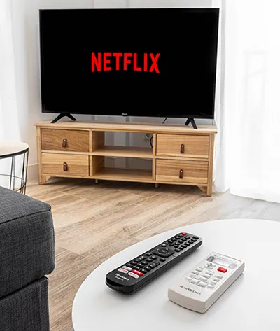 Televisor con Netflix y controles remotos sobre una mesa blanca.