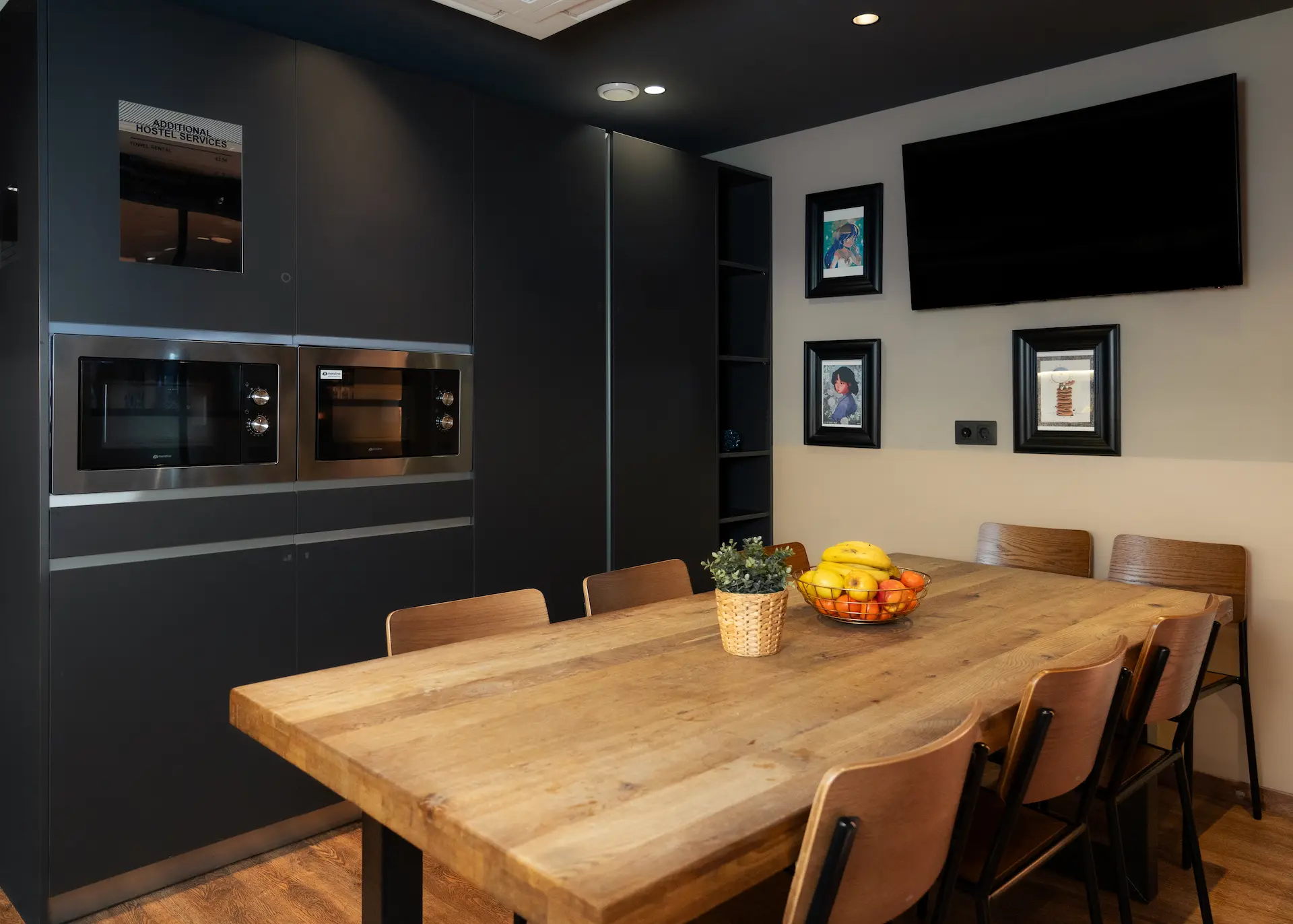 Mesa de madera en cocina moderna con microondas y frutas sobre la mesa.