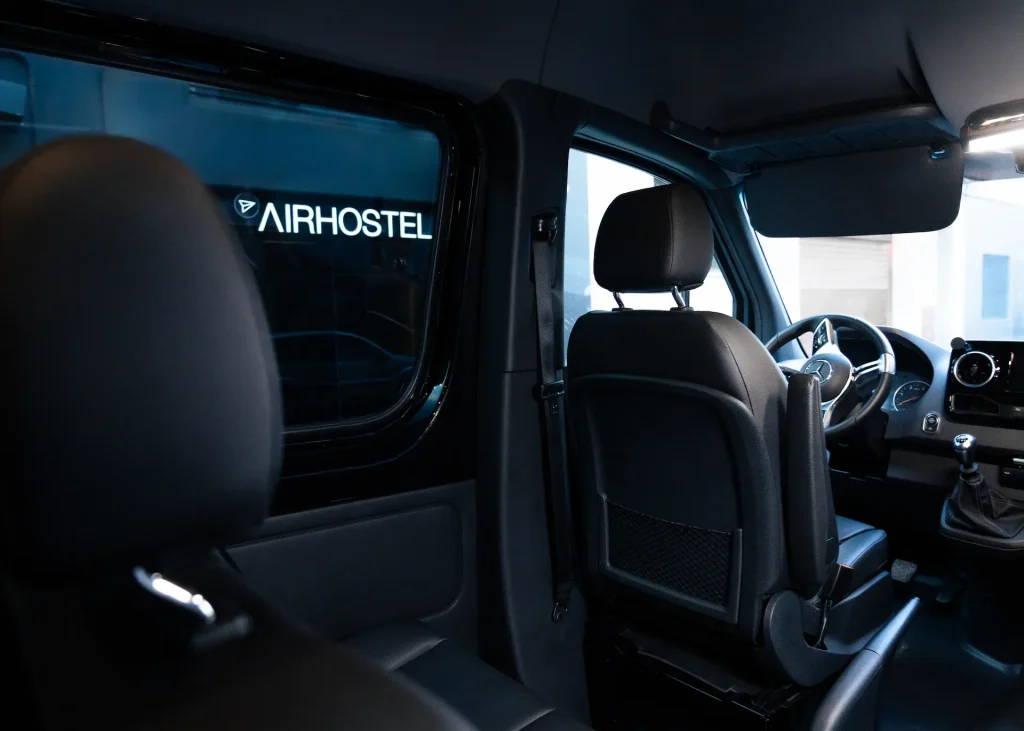 Interior de una camioneta con logo de Airhostel visto por la ventana.