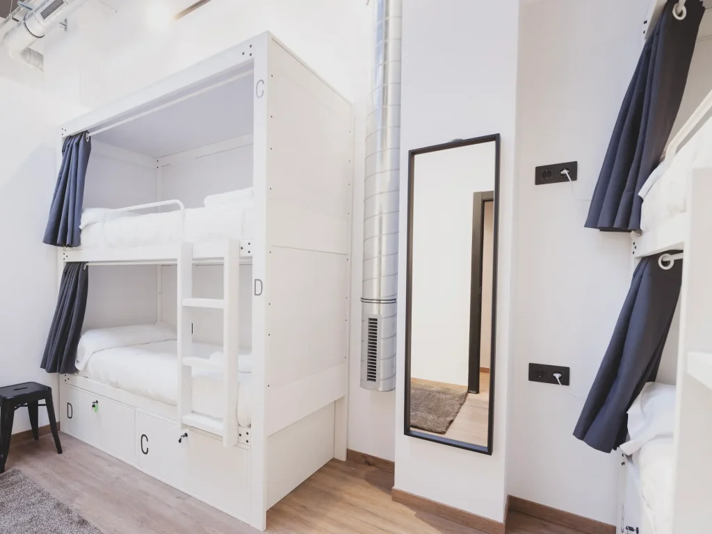 Camas litera blancas con cortinas azules en una habitaci&oacute;n moderna y luminosa.