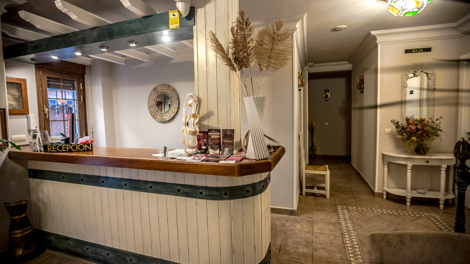 Recepci&oacute;n de un hotel con mostrador de madera y decoraci&oacute;n acogedora.