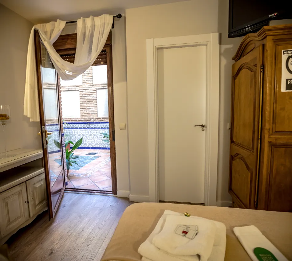Habitaci&oacute;n con puerta abierta a terraza, visibilidad a azulejos espa&ntilde;oles y planta verde.