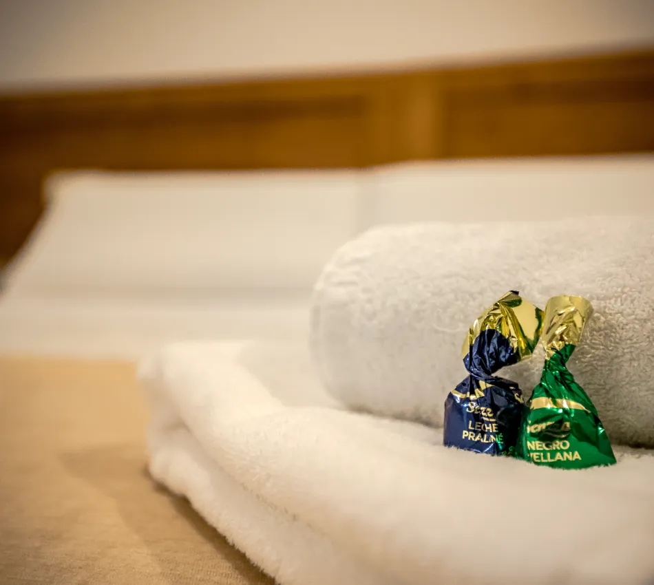 Toallas blancas con dos chocolates envueltos en papeles azul y verde.