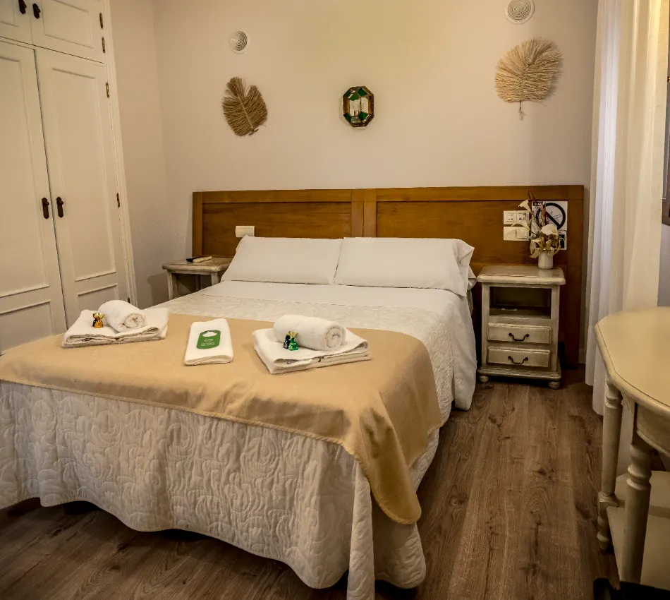 Habitaci&oacute;n de hotel con cama doble, almohadas blancas y decoraciones de pared.