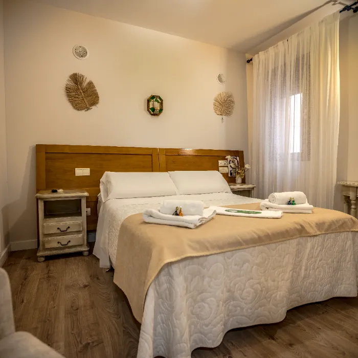Habitaci&oacute;n de hotel acogedora con cama doble, decoraci&oacute;n de pared y mesitas de noche.