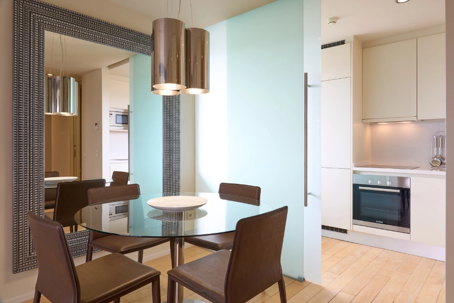 Sala de jantar moderna com mesa de vidro e cadeiras marrons.