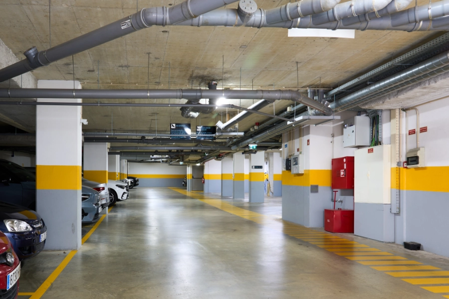 Estacionamento subterrâneo vazio com carros estacionados nas laterais.