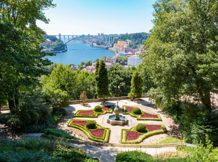 Jardim com fonte e vista do rio e ponte ao fundo.