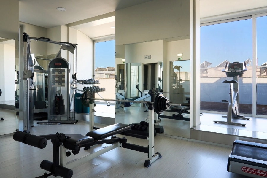 Academia com equipamentos de musculação e cardio em sala ampla e iluminada.