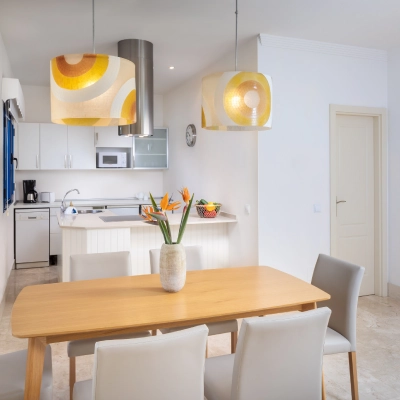 Comedor moderno con mesa de madera y l&aacute;mparas coloridas.