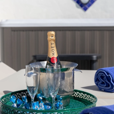Champa&ntilde;a con copas y toalla azul sobre una mesa en un ambiente soleado.