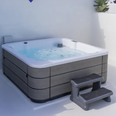 Jacuzzi cuadrado con escalera en una terraza iluminada.