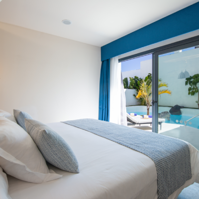 Habitaci&oacute;n moderna con cama y vista a una piscina exterior a trav&eacute;s del ventanal.