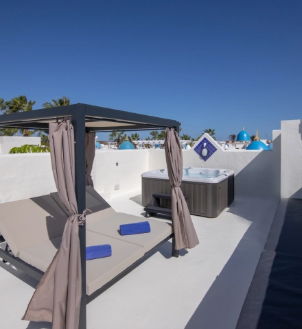 Terraza con tumbonas y jacuzzi bajo un cielo despejado.