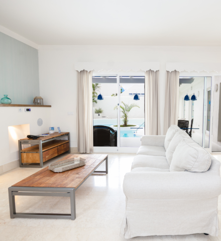 Sala elegante con sof&aacute; blanco y vista a la piscina.