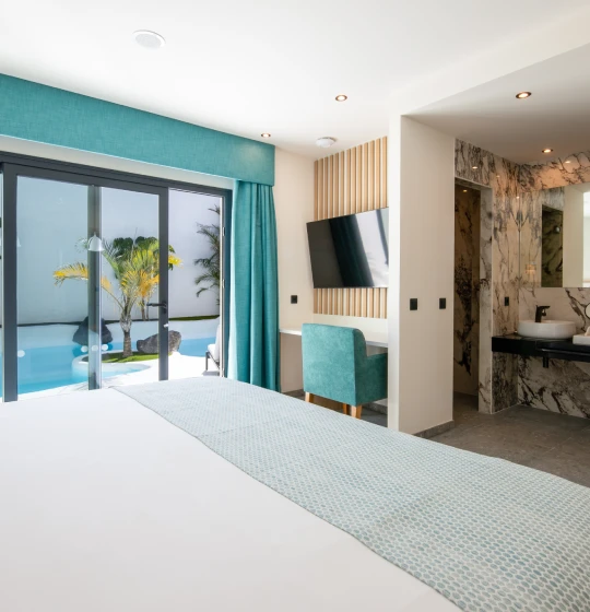 Habitaci&oacute;n moderna con cama, vista a piscina y ba&ntilde;o de m&aacute;rmol.