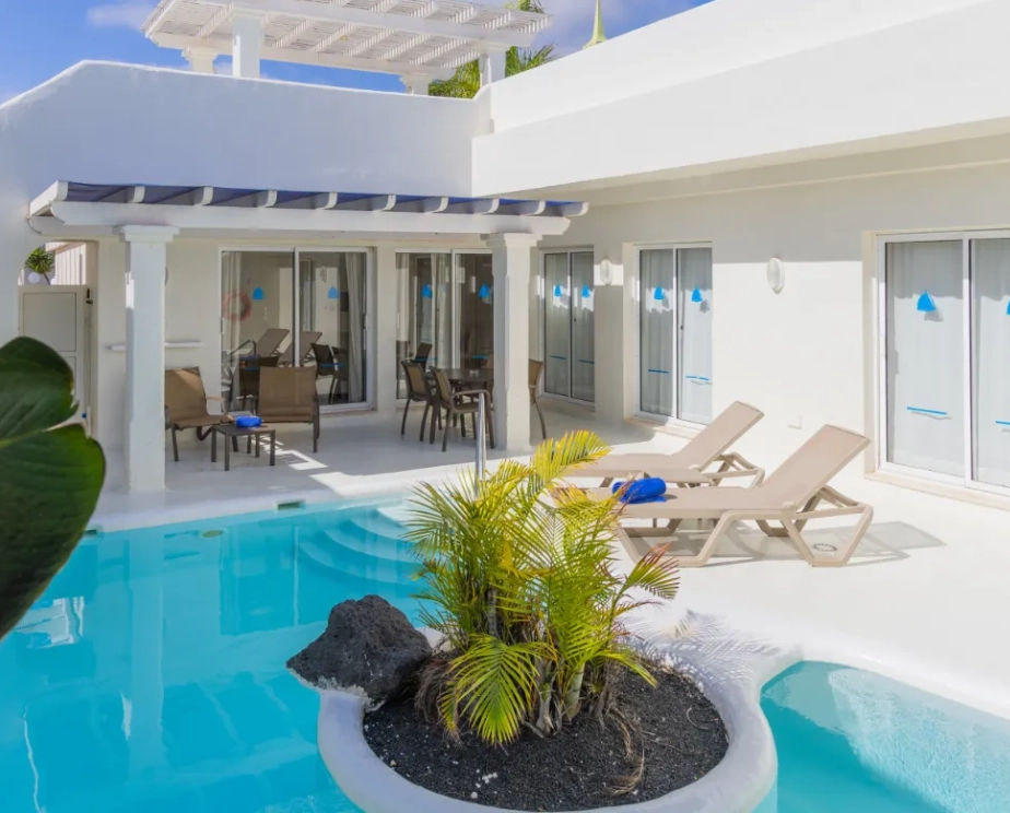 Piscina y terraza con sillones en casa blanca moderna y soleada.