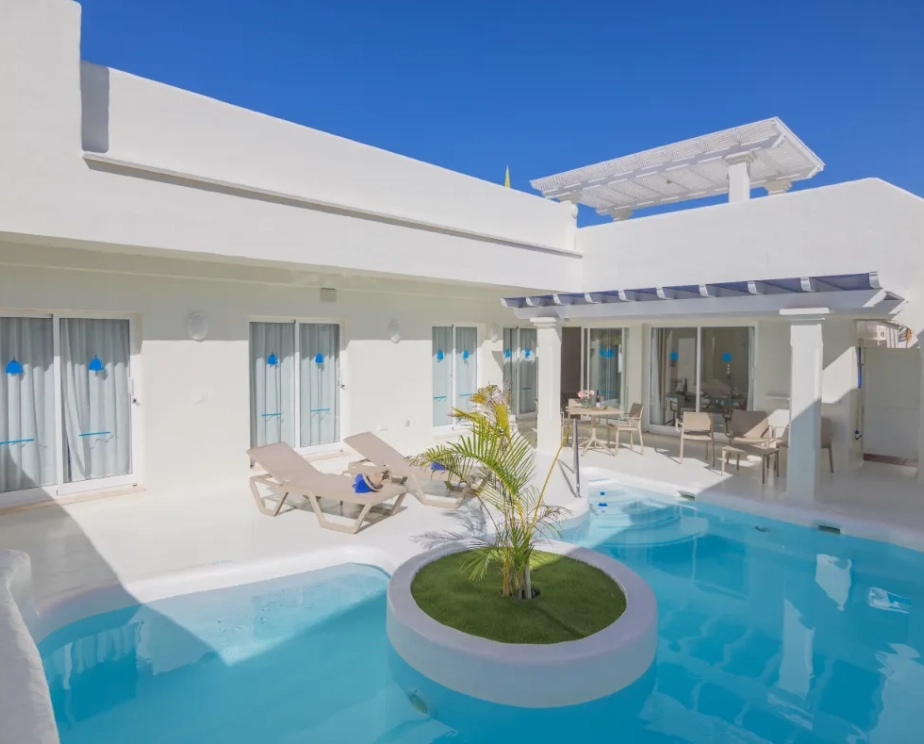 Casa blanca moderna con piscina y tumbonas.