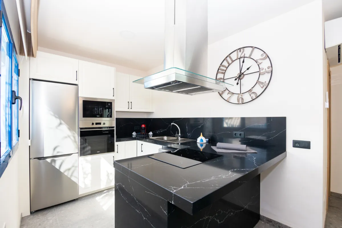Cocina moderna con encimeras negras y electrodomésticos integrados.